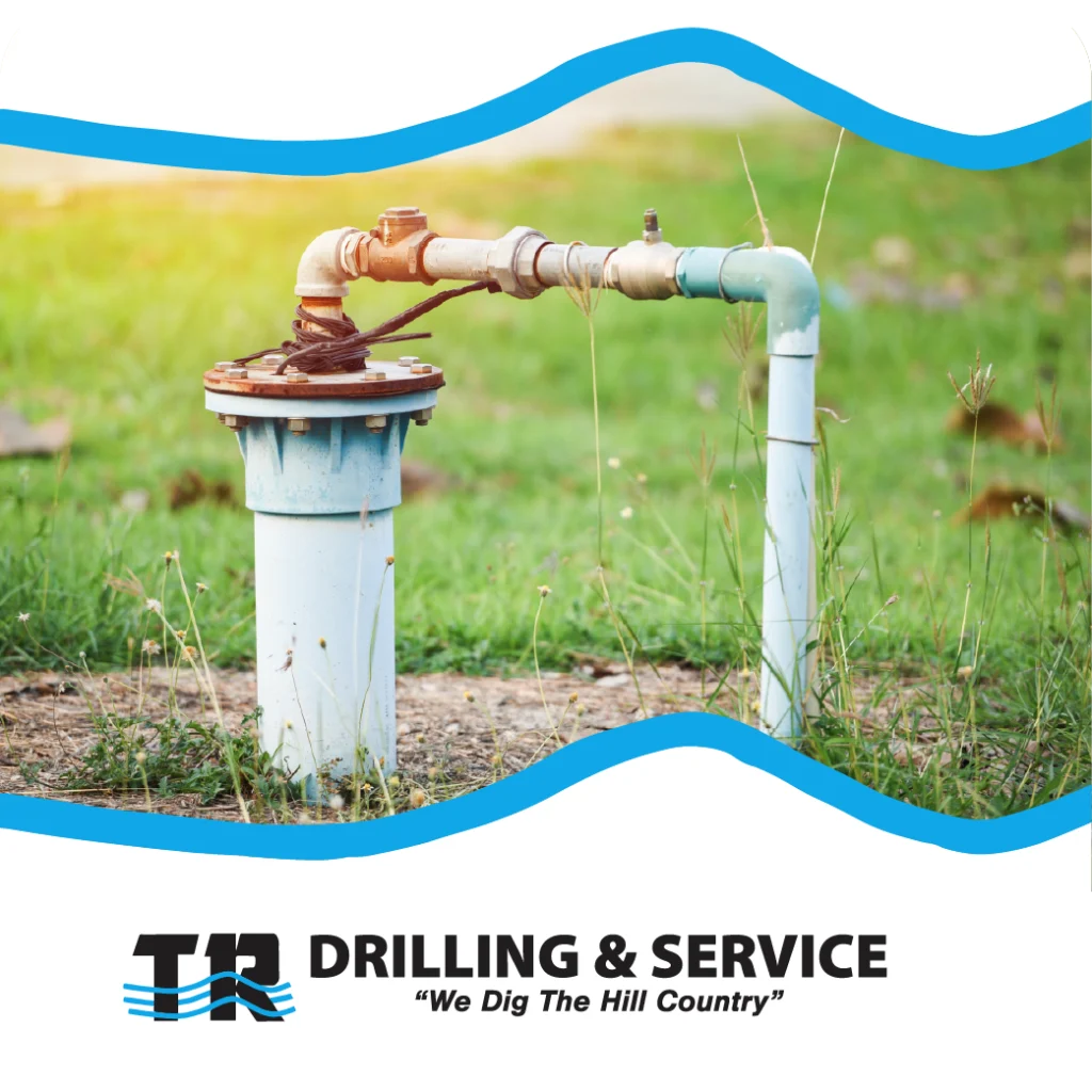 Outdoor wellhead with aging metal piping and TR Drilling & Service branding, surrounded by green grass